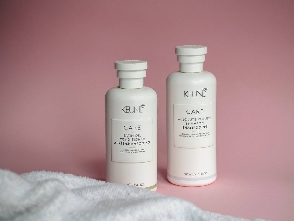 Woman applying hydrating hair care conditioner to damp hair in bathroom