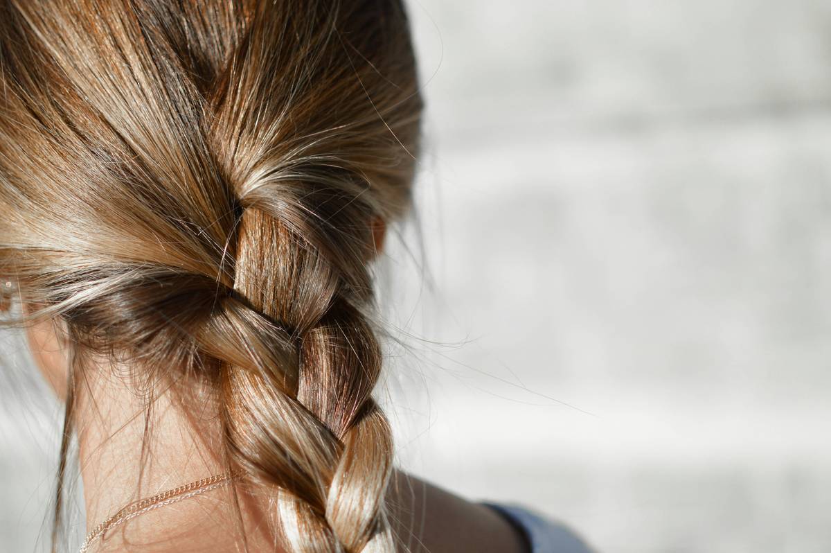 Woman using detangling conditioner on wet curly hair with wide-tooth comb