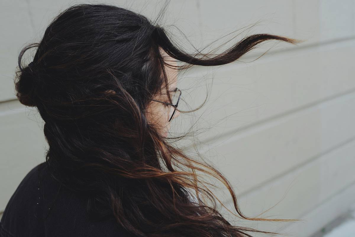 Woman applying hair conditioner only to ends of damp hair